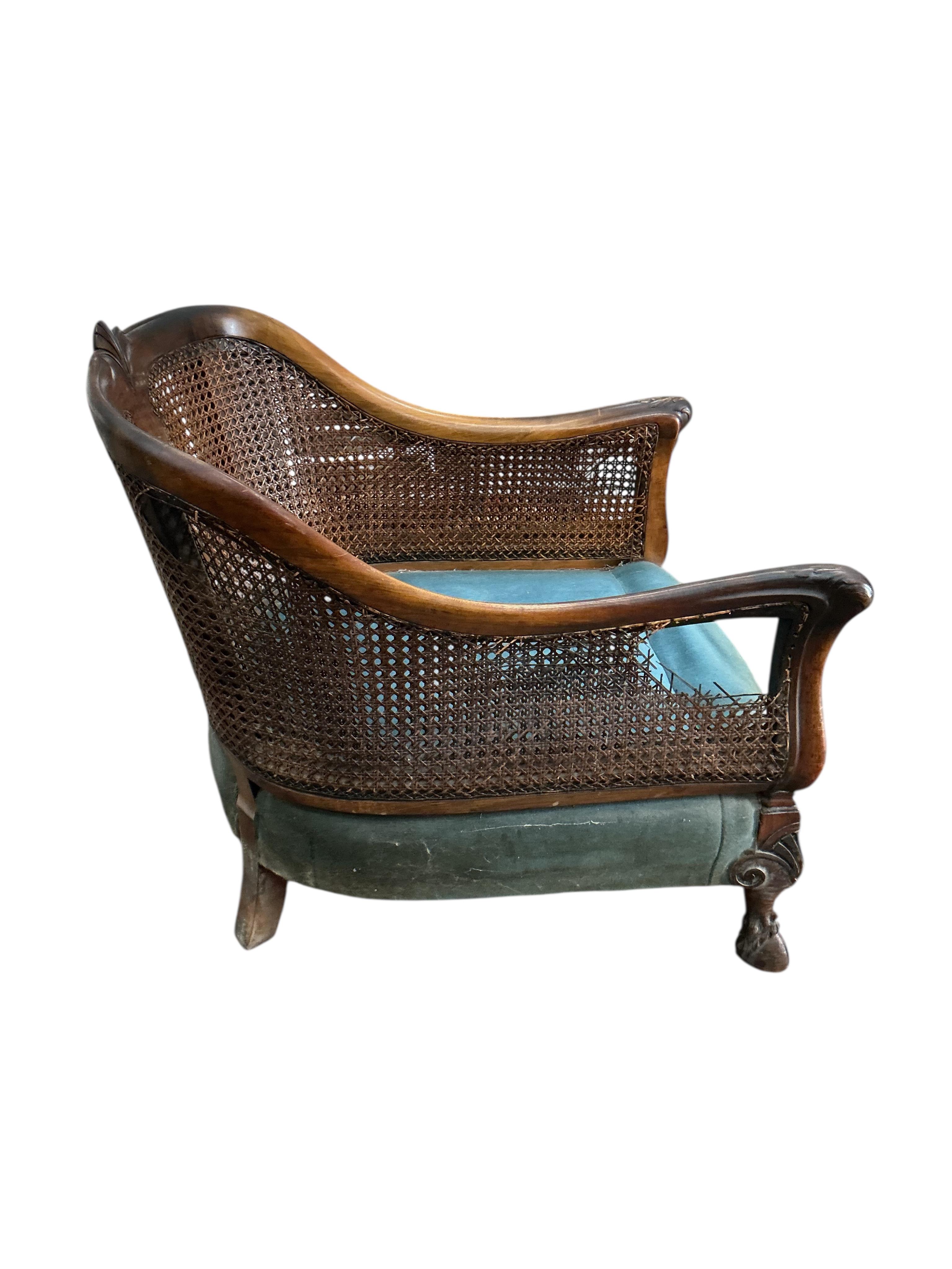 An early 20th century carved walnut and double canework three piece bergère suite, cane in need of repair